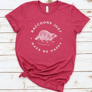 K&ouml;nnte beinhalten: Rotes T-Shirt mit einer wei&szlig;en Grafik eines Waschb&auml;ren und dem Text "Raccoons Just Make Me Happy".