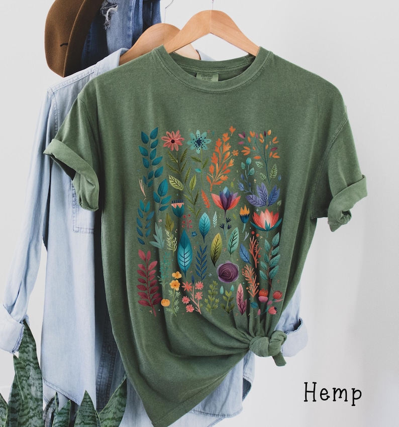 May include: A green t-shirt with a colorful floral print. The shirt is made of hemp.