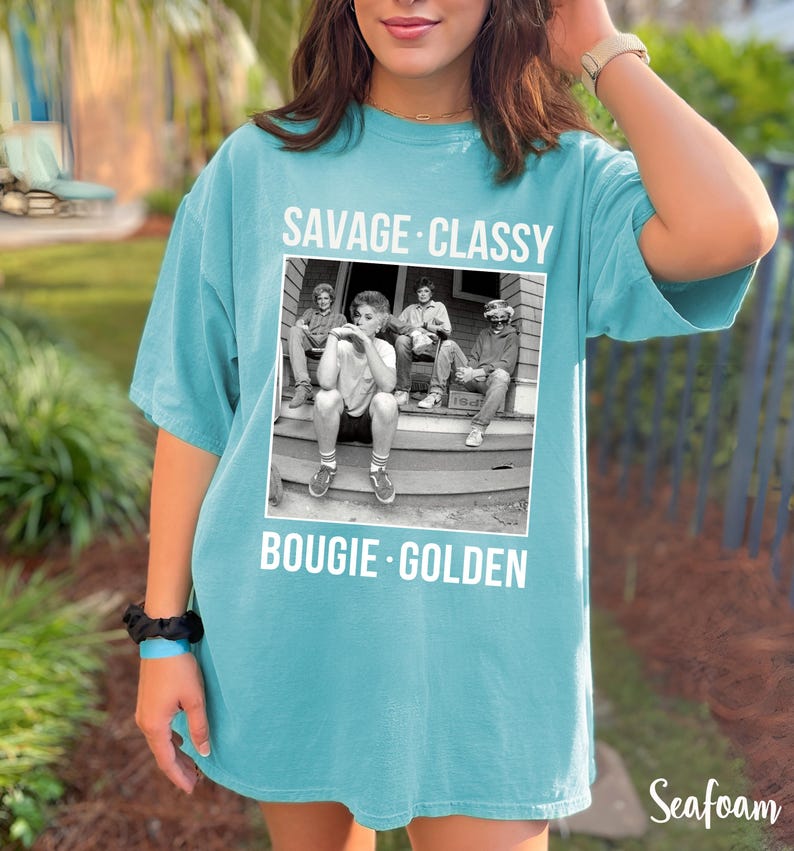 Puede incluir: Una camiseta azul turquesa con una foto en blanco y negro de cuatro personas sentadas en un porche. El texto "Savage Classy Bougie Golden" est&aacute; impreso en la camiseta.