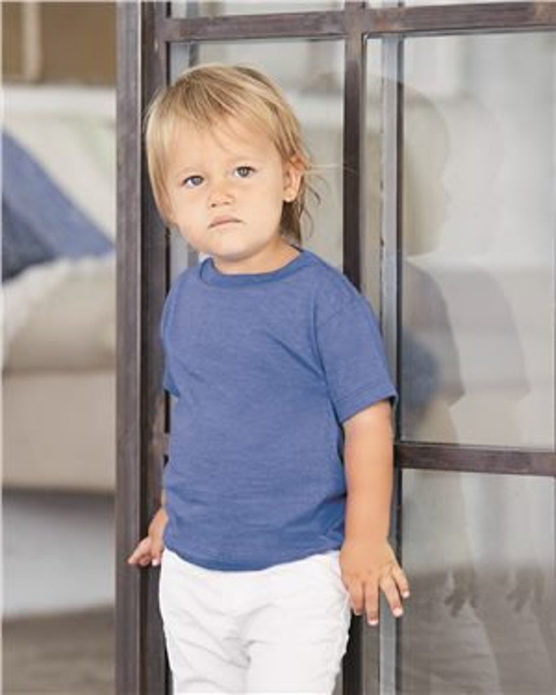 May include: A toddler wearing a light blue short-sleeved t-shirt with a distressed look. The t-shirt is made of a soft, comfortable fabric.