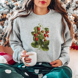 May include: A gray sweatshirt with a vintage illustration of a strawberry plant with red strawberries and green leaves.