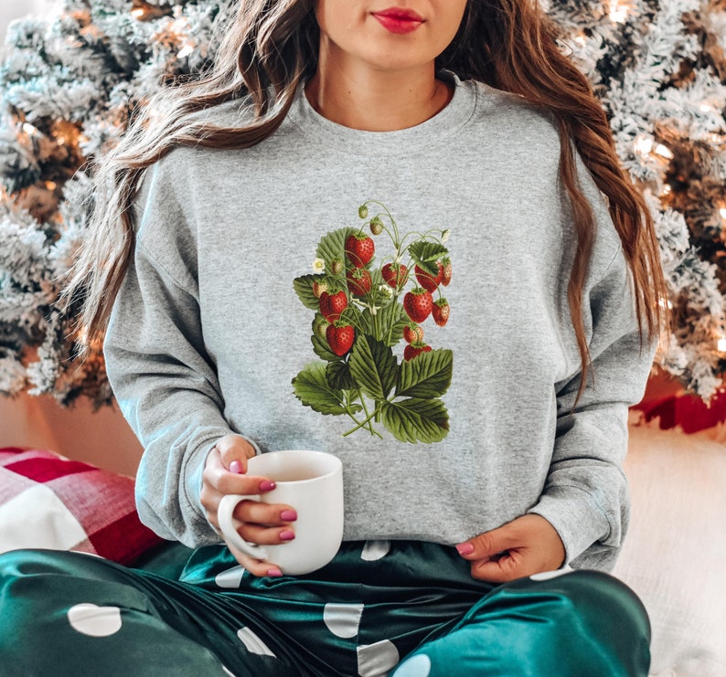 May include: A gray sweatshirt with a vintage illustration of a strawberry plant with red strawberries and green leaves.