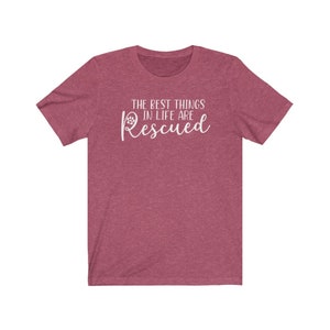 May include: A heather red t-shirt with a white paw print and the text "The best things in life are Rescued".