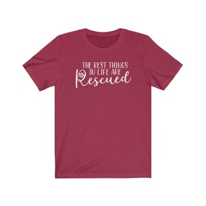 May include: A maroon t-shirt with white text that reads "The best things in life are Rescued" with a paw print symbol.
