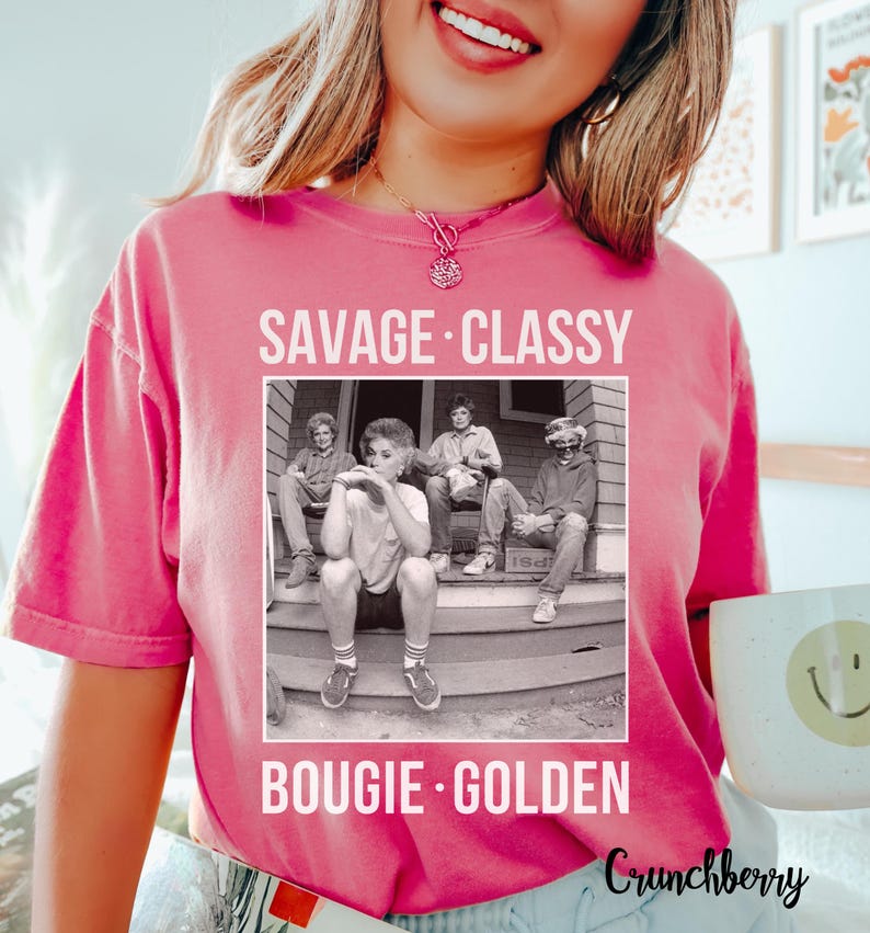 Puede incluir: Camiseta rosa con una foto en blanco y negro de cuatro personas sentadas en un porche. El texto "Savage. Classy. Bougie. Golden" est&aacute; impreso en la camiseta.