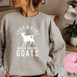May include: Gray sweatshirt with a white graphic of a goat with a red heart and the text "Just a girl who loves goats".