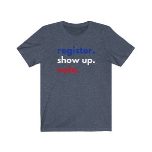 May include: A navy blue t-shirt with the text "register. show up. vote." in blue and red lettering.