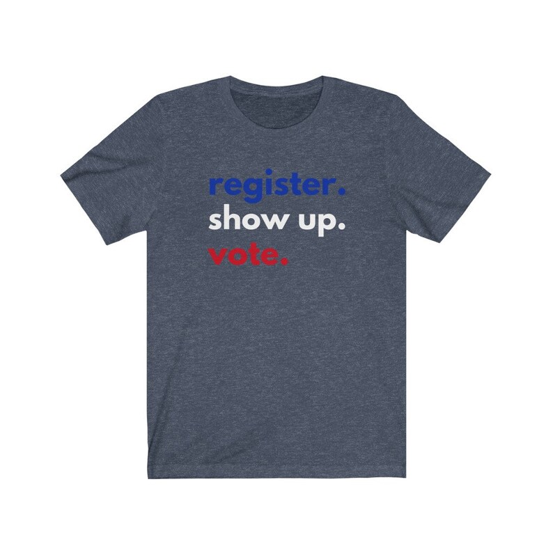 May include: A navy blue t-shirt with the text "register. show up. vote." in blue and red lettering.
