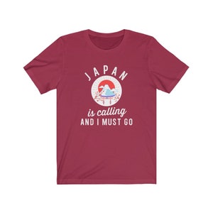 May include: Red t-shirt with a white graphic of a Japanese mountain scene and the text "JAPAN is calling AND I MUST GO."