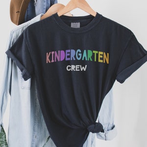 May include: Black t-shirt with the text "Kindergarten Crew" in rainbow colors.