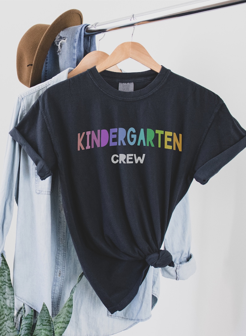May include: Black t-shirt with the text "Kindergarten Crew" in rainbow colors.