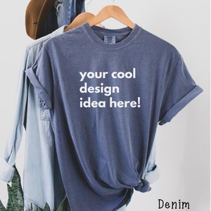 May include: A blue t-shirt with the text "your cool design idea here!" printed on the front. The shirt is hanging on a wooden hanger.