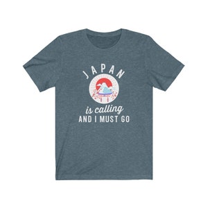 May include: A dark blue t-shirt with a white graphic of a Japanese mountain scene with a red sun and the text "JAPAN is calling AND I MUST GO".