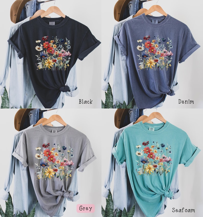 May include: A t-shirt with a floral print in shades of red, yellow, and blue. The shirt is available in four colors: black, denim, grey, and seafoam.