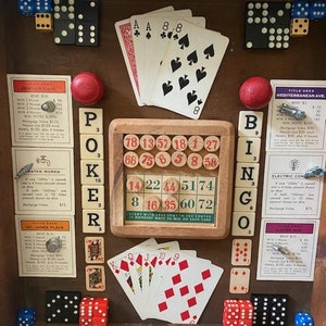 May include: A wooden box with a variety of game pieces and cards. The box contains a set of dominoes, dice, playing cards, a bingo card, and game pieces for the board game Monopoly. The box is decorated with a wooden frame and a variety of colors.
