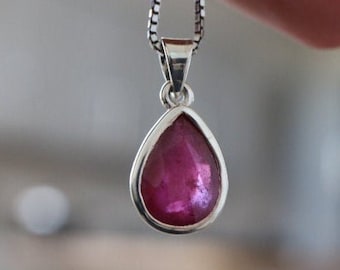 May include: A teardrop-shaped pendant necklace with a pink gemstone set in sterling silver.