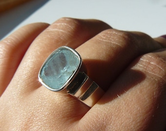May include: A silver ring with a light blue aquamarine gemstone. The ring has a simple, modern design.