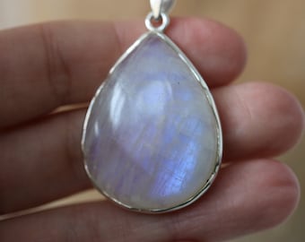 May include: A teardrop-shaped pendant with a large, iridescent moonstone set in a silver frame.