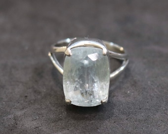 May include: A silver ring with a large, clear aquamarine gemstone set in a bezel setting.