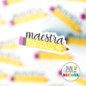 May include: A yellow pencil with a pink eraser and floral design. The word "maestra" is written in black cursive on the pencil. The pencil is a sticker with a white background.