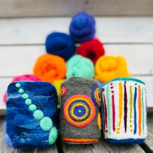 May include: Three felted wool containers with different colorful designs. The containers are blue with green dots, gray with colorful circles, and white with colorful stripes.