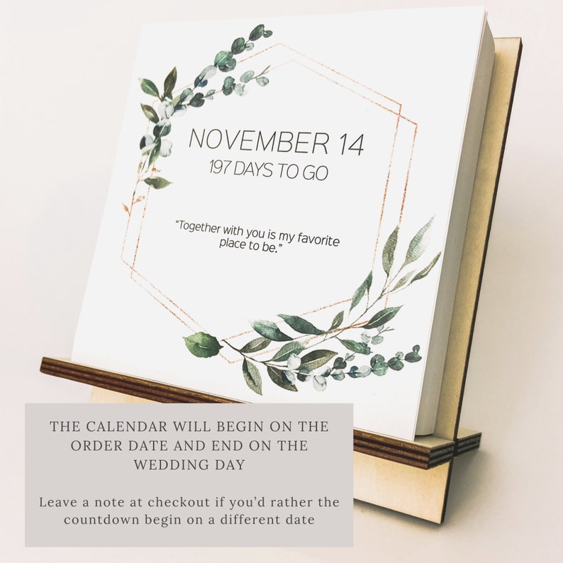 K&ouml;nnte beinhalten: Ein wei&szlig;er Countdown-Kalender mit einem goldenen sechseckigen Rahmen und gr&uuml;nem Laub. Der Kalender zeigt "NOVEMBER 14, 197 TAGE BIS ZUM TAG X" und "Mit dir zusammen zu sein ist mein Lieblingsort."