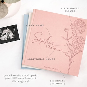 May include: A pink baby memory book with the name "Sophie" and "Georgia" printed on the cover, featuring a floral design. The book includes the optional birthdate of November 14, 2025. An ultrasound image is visible.