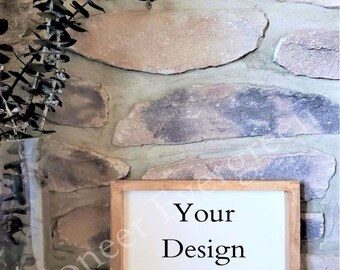 May include: A rectangular wooden sign with a white centre panel featuring the black text Your Design Here. The sign has a natural light brown wood frame and is positioned next to a clear glass vase containing dark green eucalyptus branches.