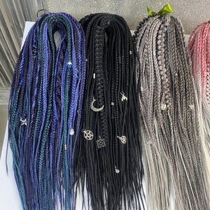 May include: Three sets of synthetic hair braids with various charms and beads. The braids are in shades of blue, black, and grey.