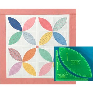 May include: A finished quilt block with a flower design in shades of pink, blue, green, yellow, and orange. The quilt block is surrounded by a red and white gingham border. The image also shows a green plastic template for cutting fabric.