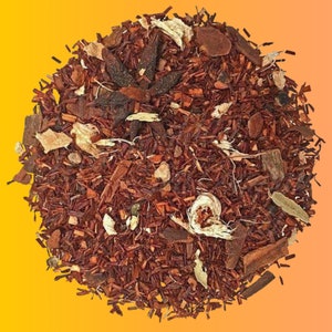 May include: A close-up of a blend of loose leaf red rooibos tea with cinnamon sticks, star anise, and pieces of ginger.