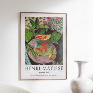 May include: A framed poster of a painting by Henri Matisse titled "Goldfish" 1912. The painting depicts a bowl of goldfish in a still life setting with green plants and flowers.