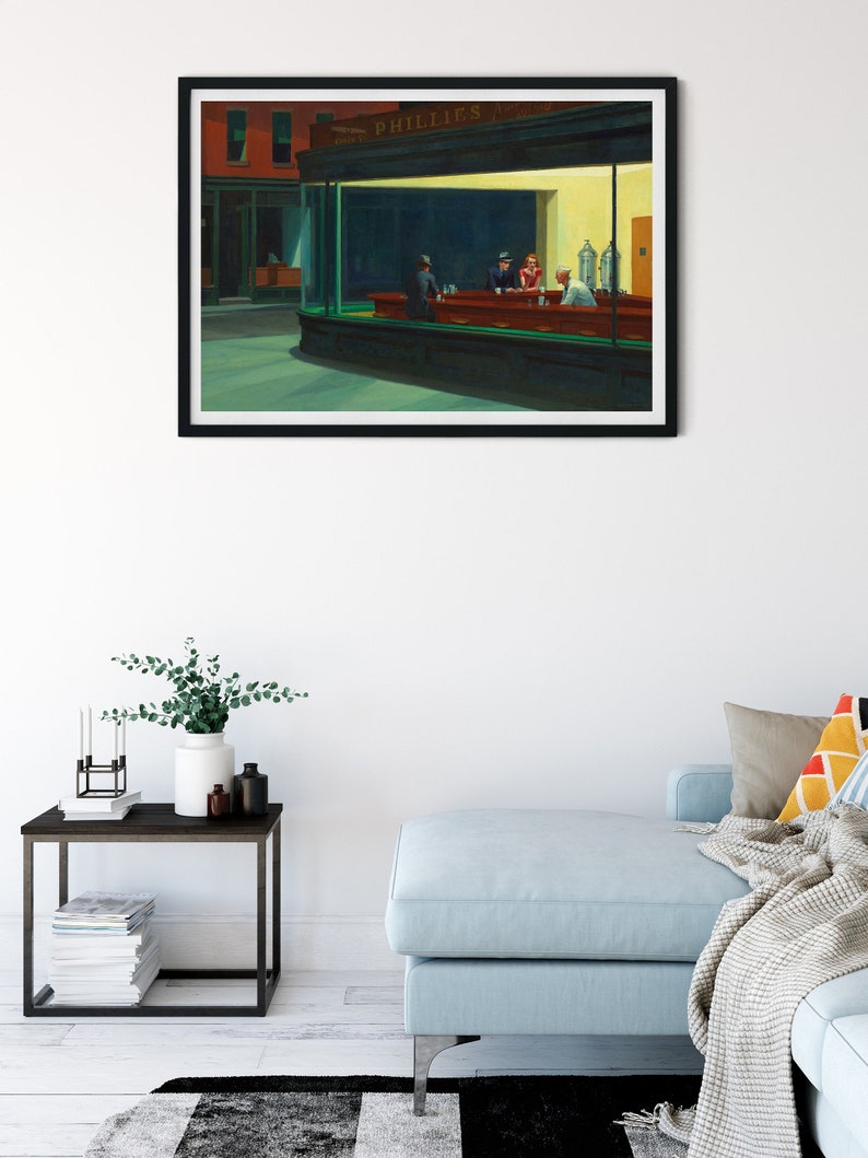 May include: A framed print of Edward Hopper's "Nighthawks" painting. The artwork depicts a diner scene with figures at the counter, bathed in the glow of artificial light. The diner is set on a street corner, with the word "PHILLIES" visible on the awning.