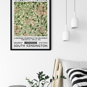 May include: A black and white poster with the text "WILLIAM MORRIS" at the top. The poster features a floral design with green leaves and white flowers. The text "A CENTENARY EXHIBITION AT THE V&A MUSEUM FEBRUARY 10th - APRIL 8th, 1934 NEAREST UNDERGROUND STATION SOUTH KENSINGTON" is at the bottom of the poster.
