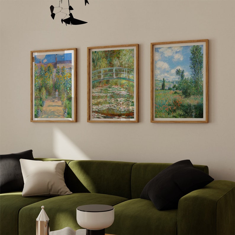 May include: Three framed paintings of landscapes. The leftmost painting shows a garden with a path leading to a house. The middle painting shows a bridge over a pond with water lilies. The rightmost painting shows a field with a village in the distance.