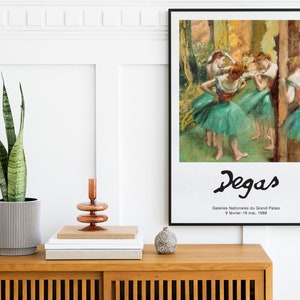 May include: A framed poster of a painting by Edgar Degas depicting dancers in a ballet studio. The poster is titled "Degas" and includes the text "Galeries Nationales du Grand Palais 9 fevrier - 16 mai, 1988".