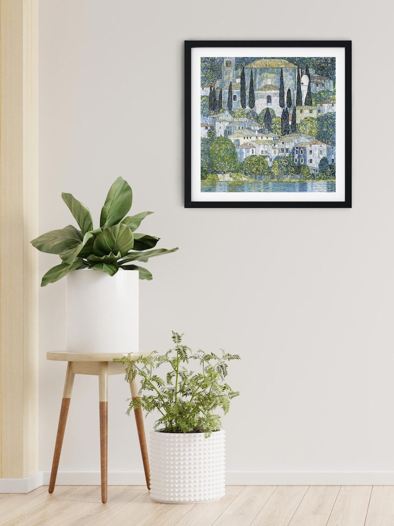 Puede incluir: Una pintura enmarcada que representa una escena de pueblo con una iglesia, &aacute;rboles y un lago. La pintura est&aacute; realizada en estilo puntillista, con peque&ntilde;os puntos de color que crean la imagen.
