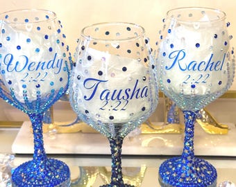 May include: Three personalized wine glasses with blue crystal embellishments. Each glass has a name and the number 2:22 in blue script. The stems and bases are covered in blue crystals, and the rims are dotted with blue and clear gems.