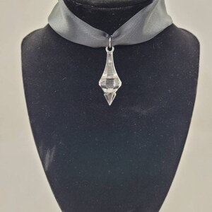 May include: A black satin choker necklace with a clear crystal pendant.