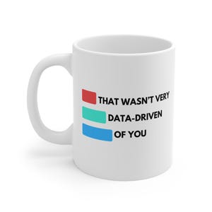 Puede incluir: Taza de cerámica blanca con asa curva. La taza presenta el texto "THAT WASN'T VERY DATA-DRIVEN OF YOU" en negro, con acentos rectangulares rojos, turquesa y azules. Un regalo humorístico.