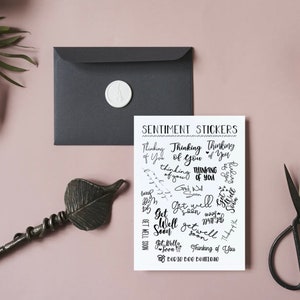 Puede incluir: Una hoja de papel blanco con texto negro que dice "Sentiment Stickers" y presenta una variedad de pegatinas con frases como "Thinking of You" y "Get Well Soon".