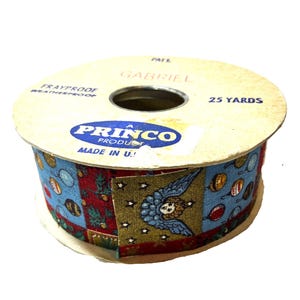 May include: A spool of ribbon featuring a repeating pattern of blue angels, stars, and Christmas ornaments on red and blue backgrounds. The cardboard spool is labeled Princo Product, Frayproof, Weatherproof, Gabriel, and 25 Yards, Made in U.S.A.