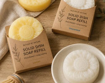 May include: Two round yellow and white solid dish soap refills in brown cardboard boxes labeled Bloved by Nature Solid Dish Soap Refill Plant-Based Long Lasting Lemon and Unscented, with two additional soap bars and a wooden dish brush.