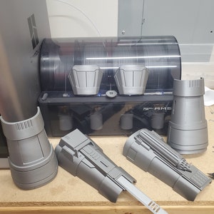 May include: A set of five 3D printed grey plastic pieces, including two arm pieces, two smaller pieces, and one larger piece with a blade. The pieces are on a wooden surface.