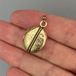 May include: A gold oval locket with a rope design and floral engravings.