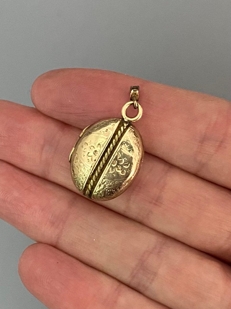 May include: A gold oval locket with a rope design and floral engravings.
