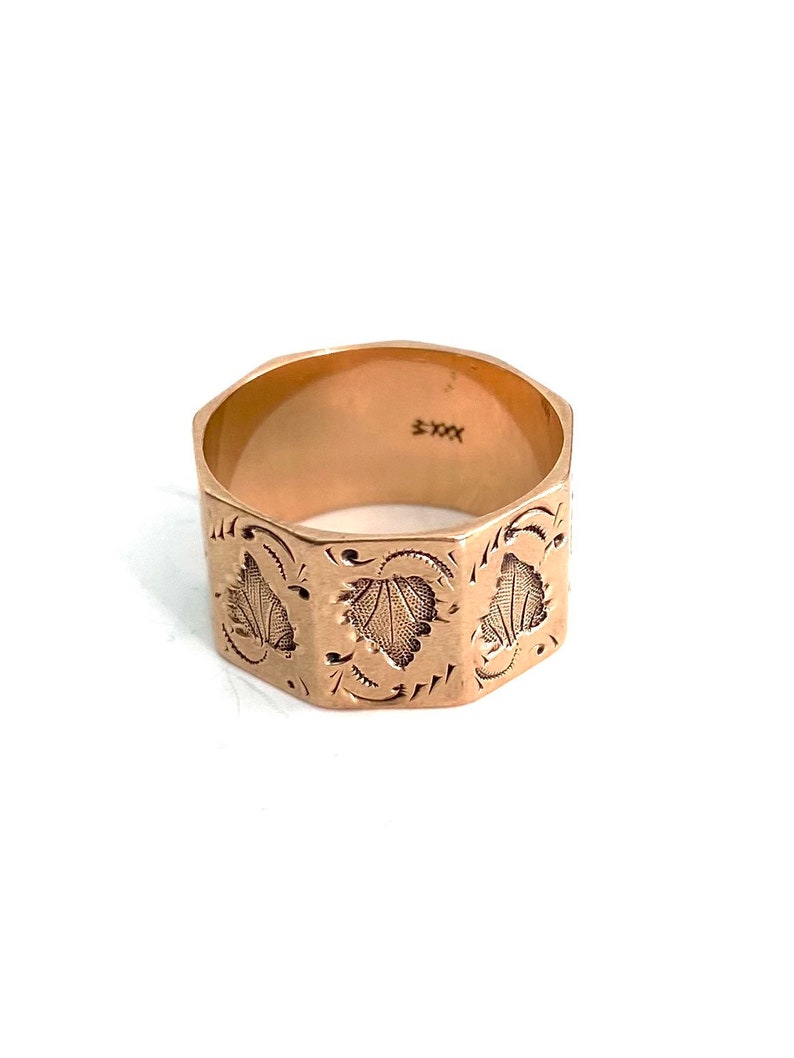 May include: A gold ring with a hexagonal band and a floral design. The inside of the band is marked with "5XX".