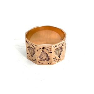 May include: A gold ring with an octagonal band and a detailed engraved design of leaves and swirls.