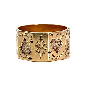 May include: A gold band ring with an intricate engraved design featuring floral motifs and geometric patterns.