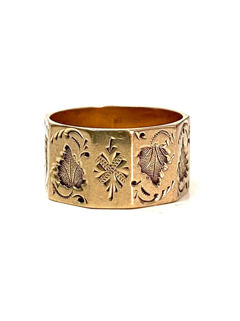 May include: A gold band ring with an intricate engraved design featuring floral motifs and geometric patterns.